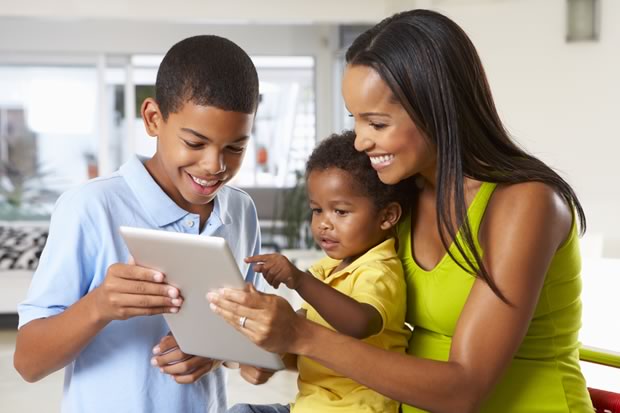 mother and two sons holding and browsing websites on a tablet