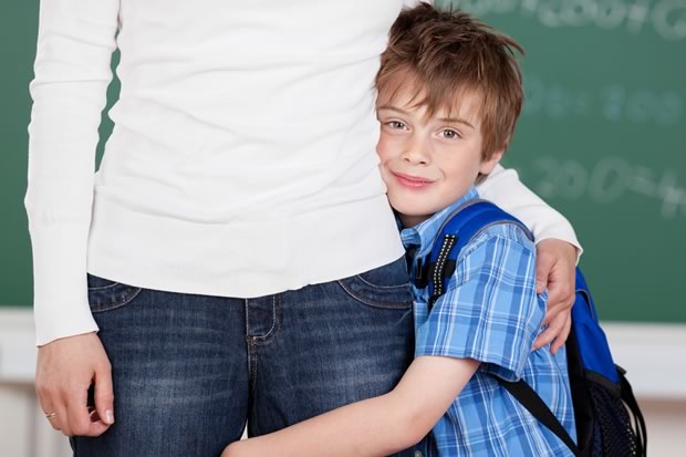 autistic child holding on to their parents leg at school